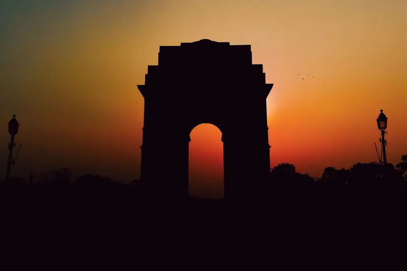 India Gate in New Delhi silhouetted against an orange sunset sky